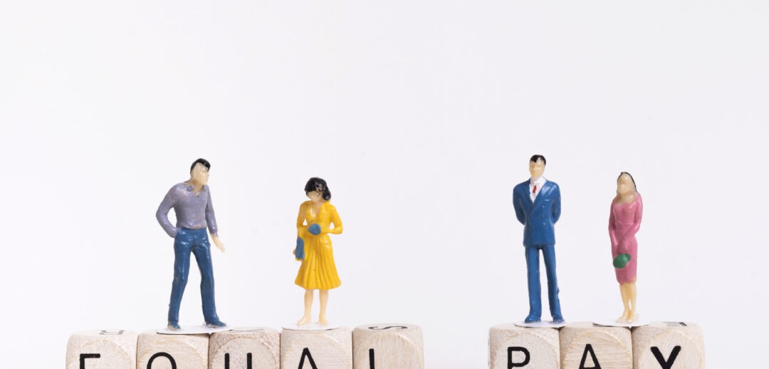 business-man-and-woman-sitting-on-wooden-cubes-with-equal-pay-written-1080x675