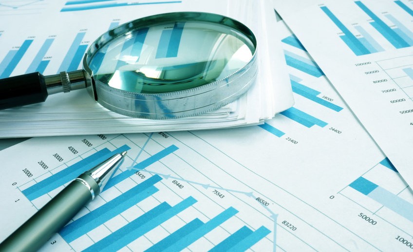 Assessment and audit. Business papers with financial charts and Magnifying glass.