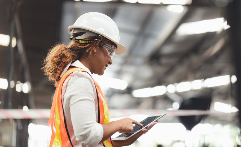 Close up hand industrial industrial plant with a tablet in hand, Engineer looking of working at industrial machinery setup in factory.